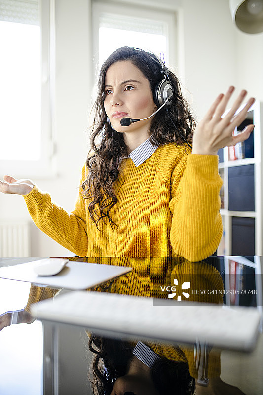 疲惫的女心理医生佩戴耳机看着镜头，远程在线医疗聊天咨询，远程医疗服务，虚拟医生电话会议概念图片素材