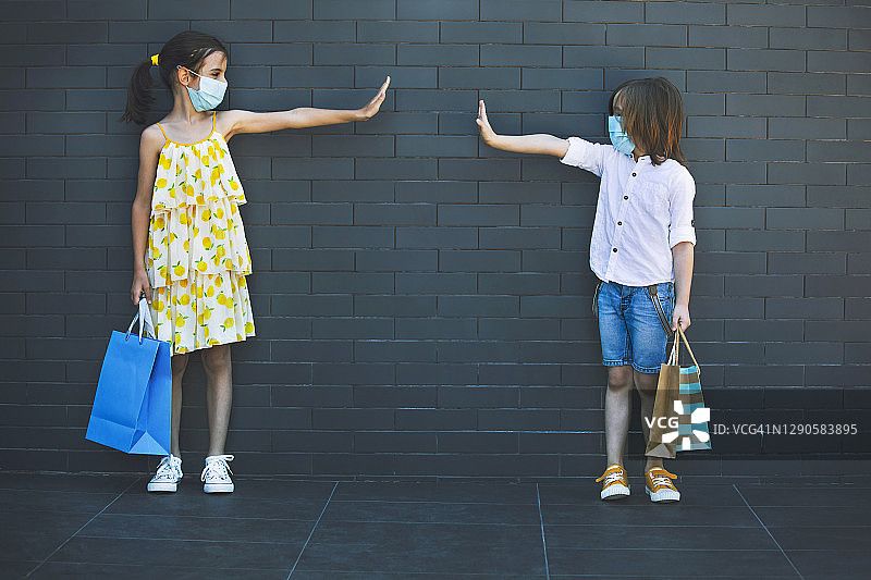 两个戴着口罩的孩子提着购物袋图片素材