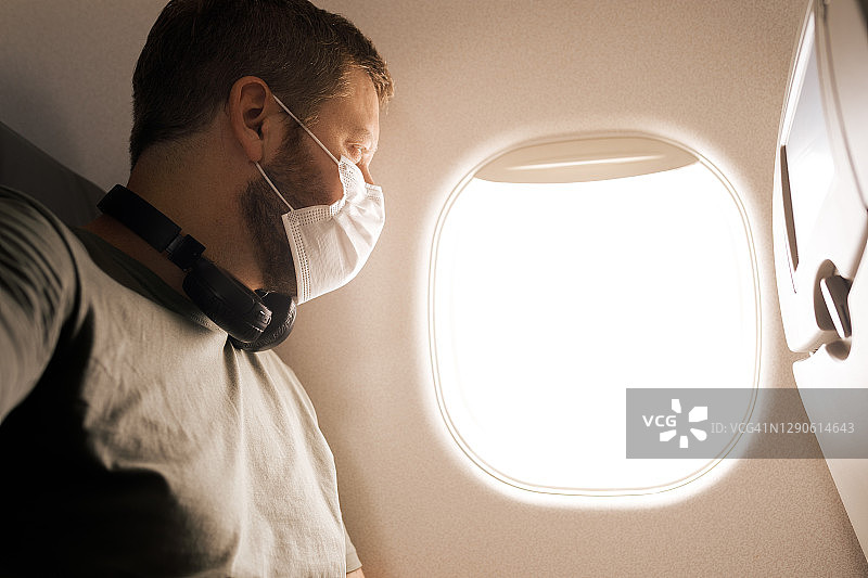 男子戴着口罩乘飞机旅行图片素材