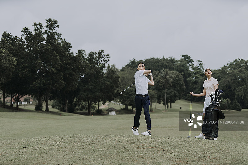 中国成熟男人在高尔夫球场开球，他的朋友在观察图片素材