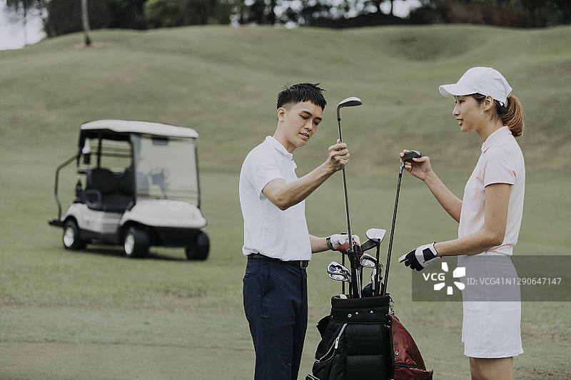 亚洲华人夫妇在高尔夫球场打开高尔夫设备图片素材