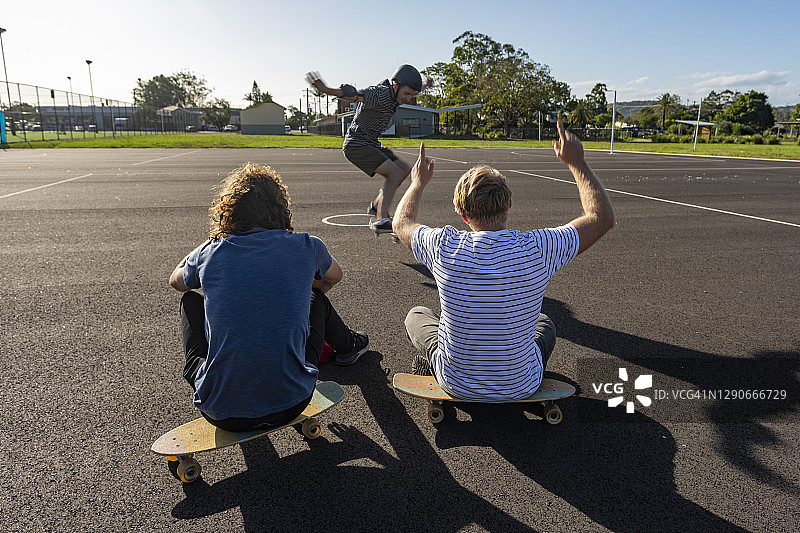 朋友们为玩滑板的滑板手欢呼图片素材