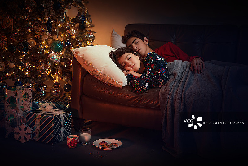 圣诞之夜孩子们在沙发上睡觉，试图抓住圣诞老人图片素材