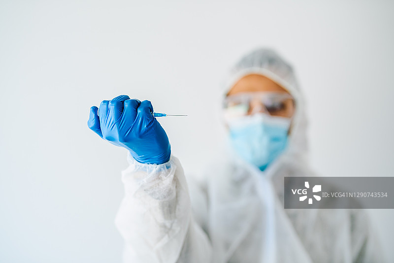 医生/医务人员手持疫苗注射器。冠状病毒疫苗接种概念。图片素材