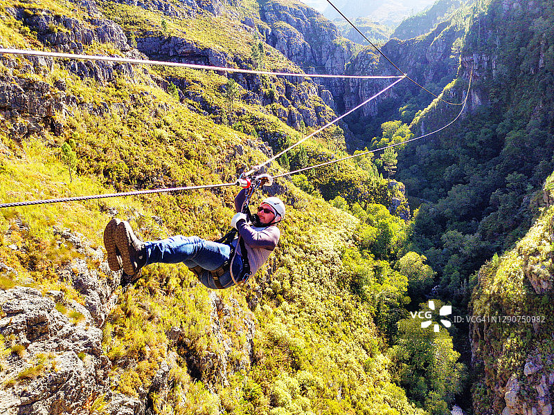 在南非霍屯督荷兰自然保护区滑索的年轻男人图片素材