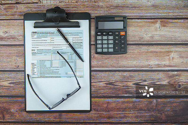 办公桌上印制的税务表格，配有计算器和笔图片素材