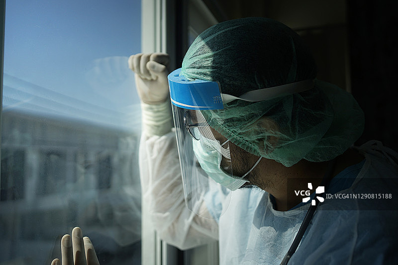 亚洲男医生戴着面罩和PPE防护服，筋疲力尽，停止冠状病毒爆发或Covid-19的概念，Covid-19隔离概念图片素材