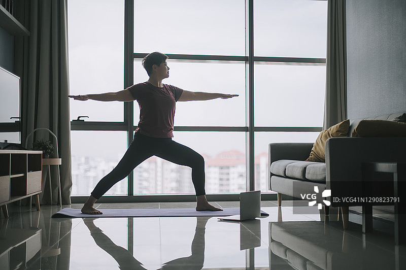 周末早晨，中国亚洲美丽女性在家中客厅瑜伽垫上冥想锻炼的剪影图片素材