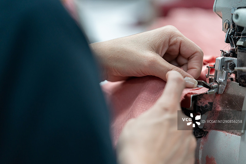 缝纫女工在纺织厂缝制衣服的特写图片素材
