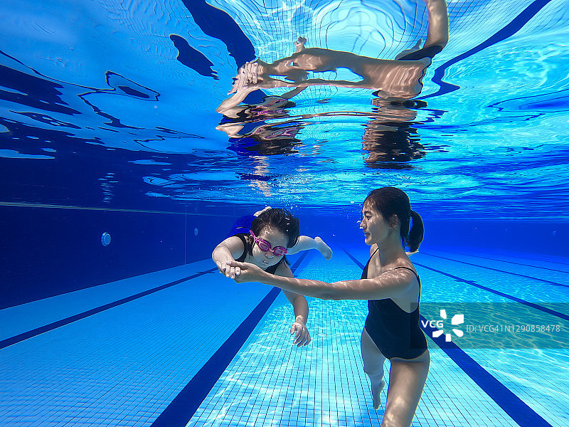 亚洲华裔游泳女教练手把手教小女孩做游泳呼吸练习图片素材