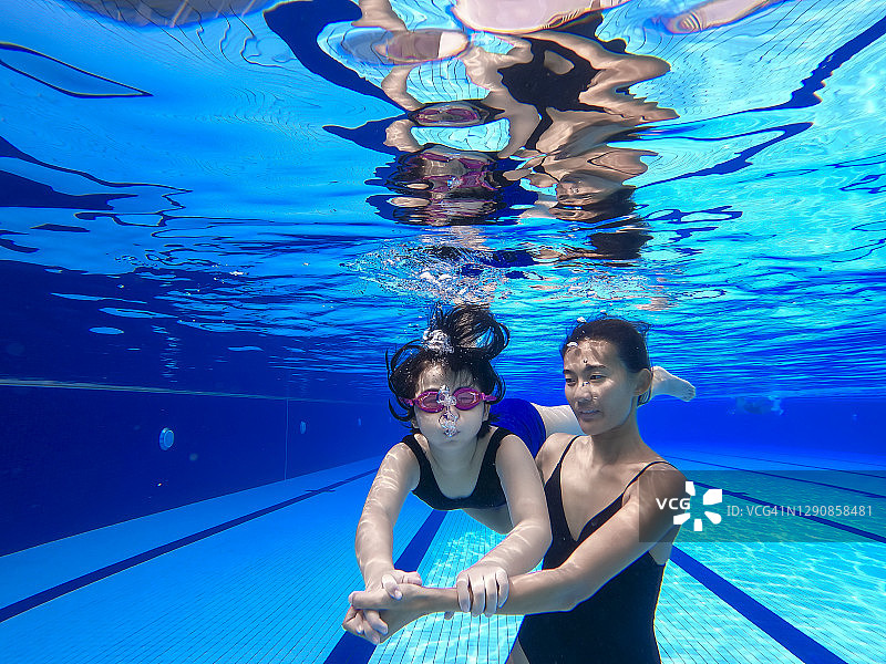 亚洲华裔游泳女教练手把手教小女孩做游泳呼吸练习图片素材