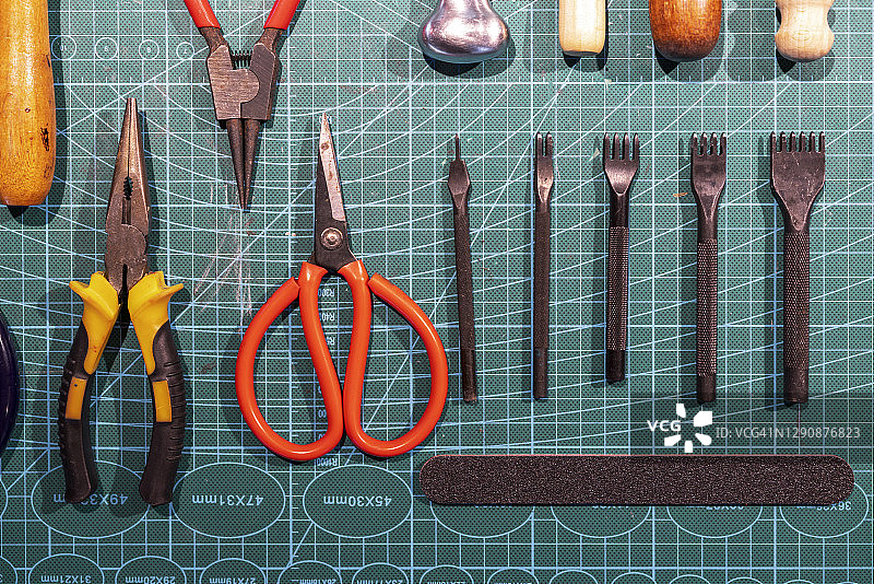 网格图案桌上的皮革加工工具图片素材