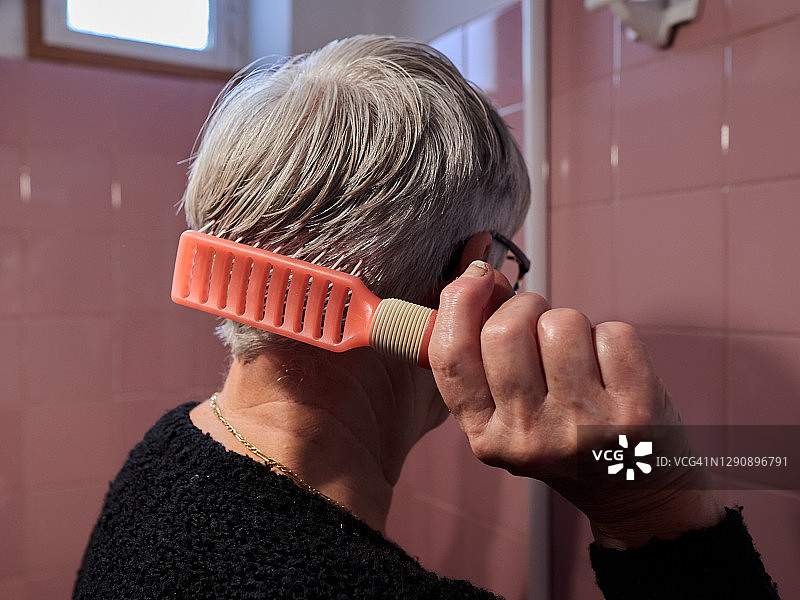 年长的白人女人在家中浴室梳理头发图片素材