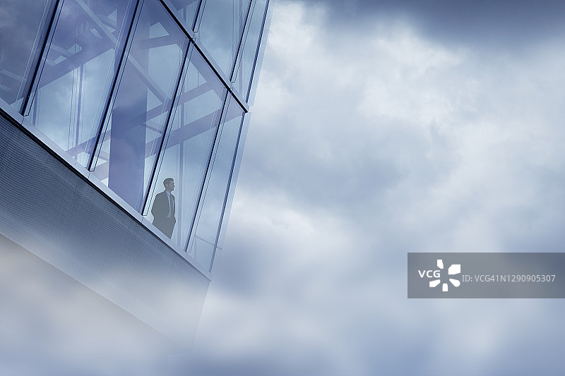 在云雾笼罩的办公楼里向外看的商人图片素材