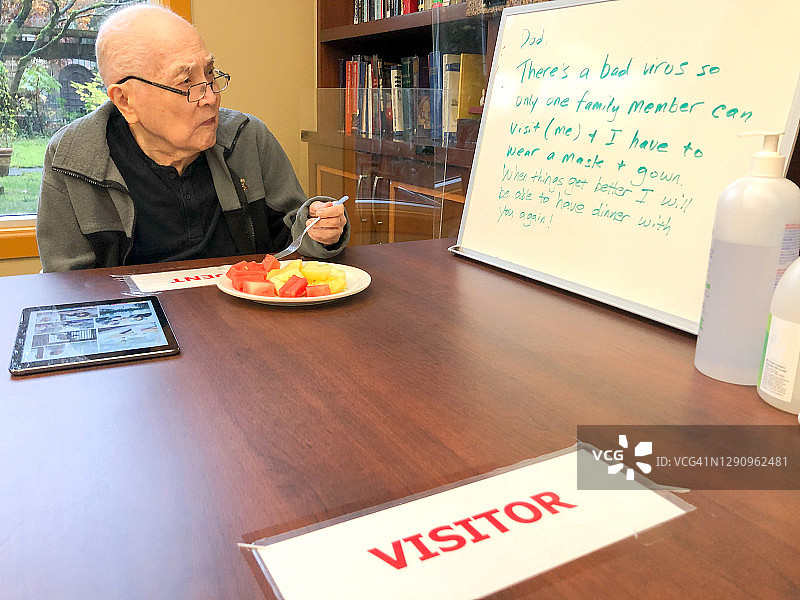 疫情期间的家庭团聚，在护理院的父亲正在阅读信息图片素材