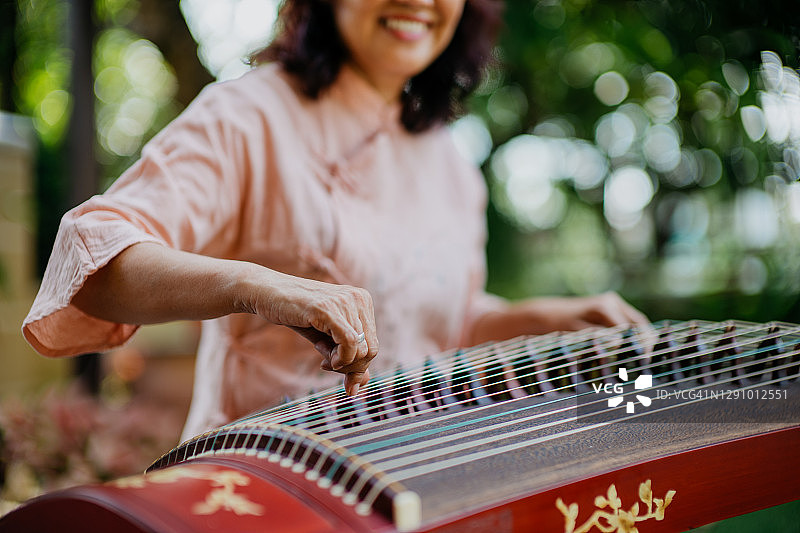 年长的女人在户外练习古筝图片素材