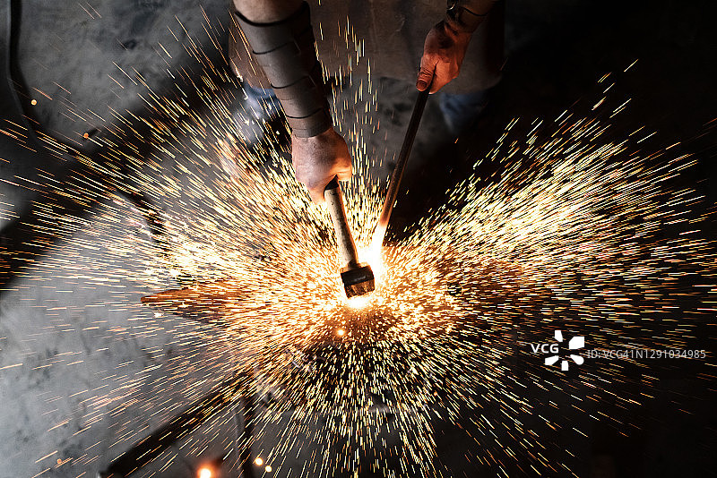 经验丰富的铁匠在工作室内锻造新作品图片素材