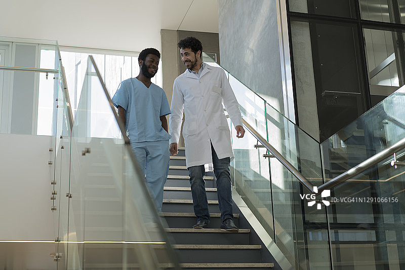 医生和黑人男护士在医院的楼梯上边走边聊图片素材