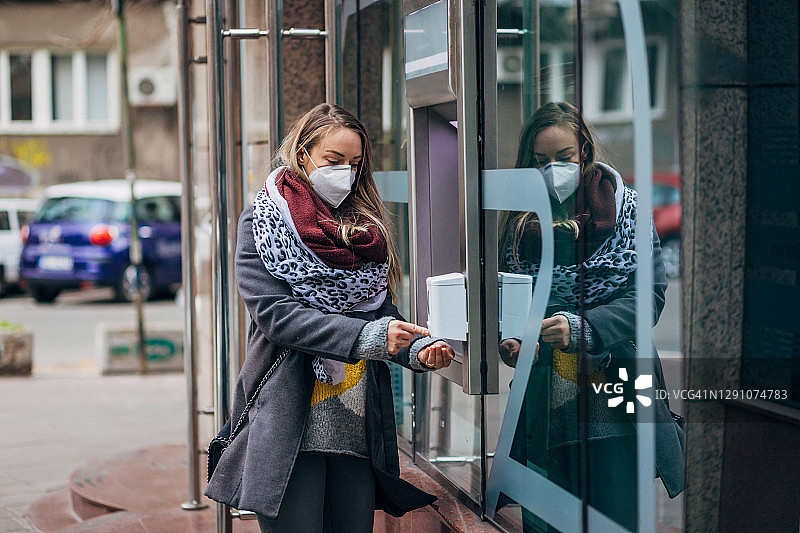 从ATM机成功取款后，负责任的女人用洗手液消毒图片素材