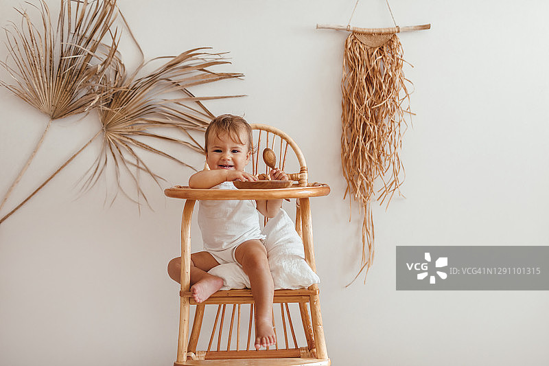 可爱的女宝宝坐在生态木制儿童餐椅上，婴儿房采用天然有机材料，零浪费理念图片素材