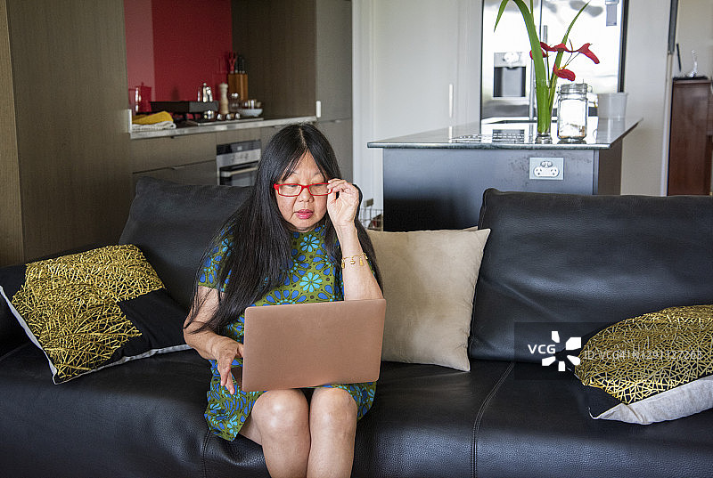 阅读电脑上所写内容的亚裔中年妇女图片素材