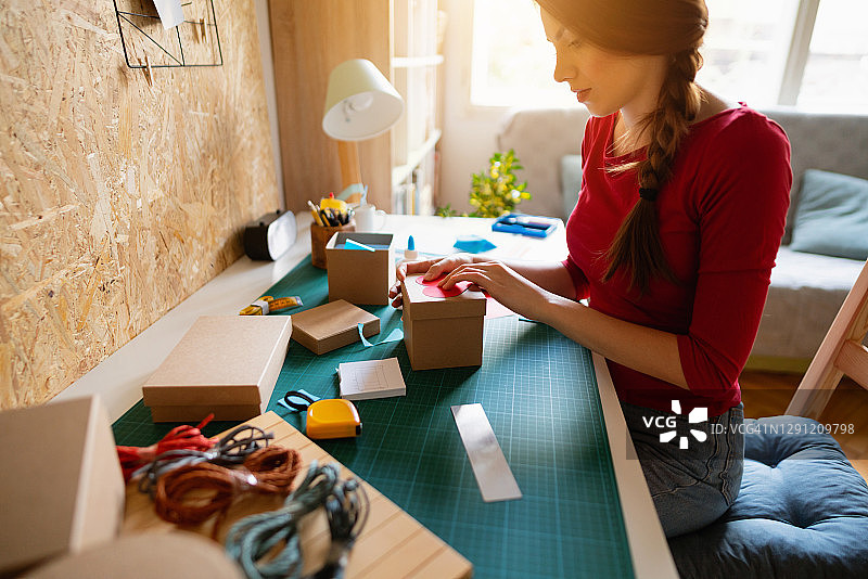 年轻女子坐在桌旁制作装饰礼品盒图片素材