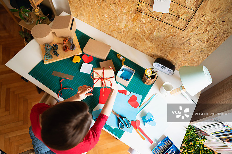 一位坐在工作台旁制作礼品盒的身份不明的女性的俯视图图片素材