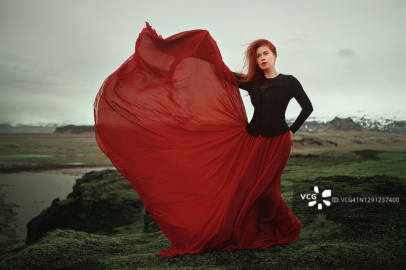 穿着红色裙子的女人在海岸线上摆姿势图片素材