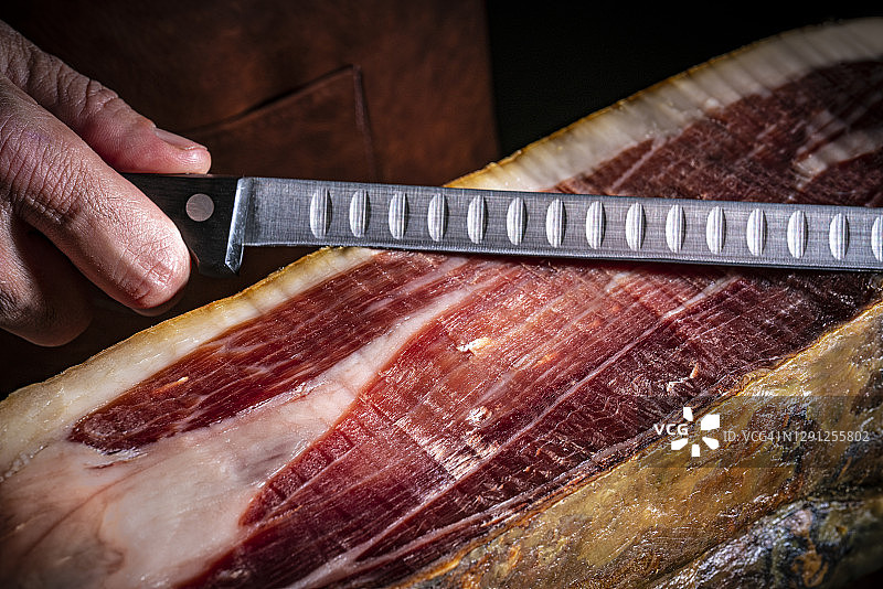 伊比利亚火腿：男屠夫在昏暗背景下持刀图片素材