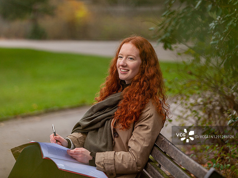 在公园长椅上学习的微笑少年学生图片素材