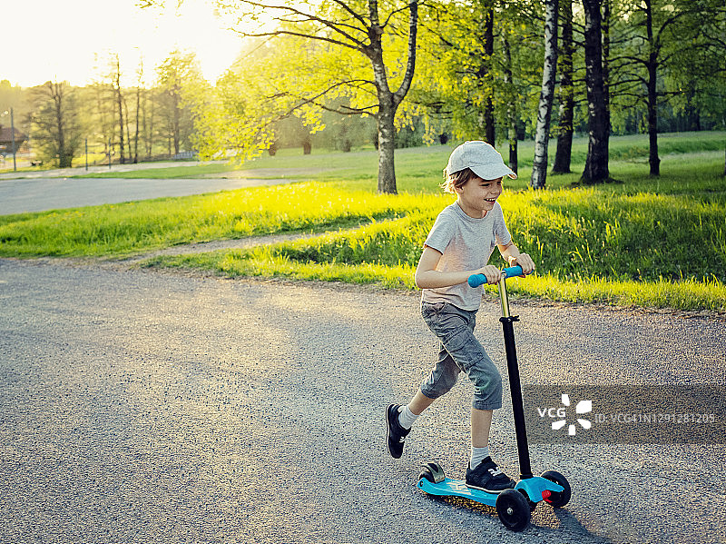 快乐的男孩在户外玩滑板车图片素材