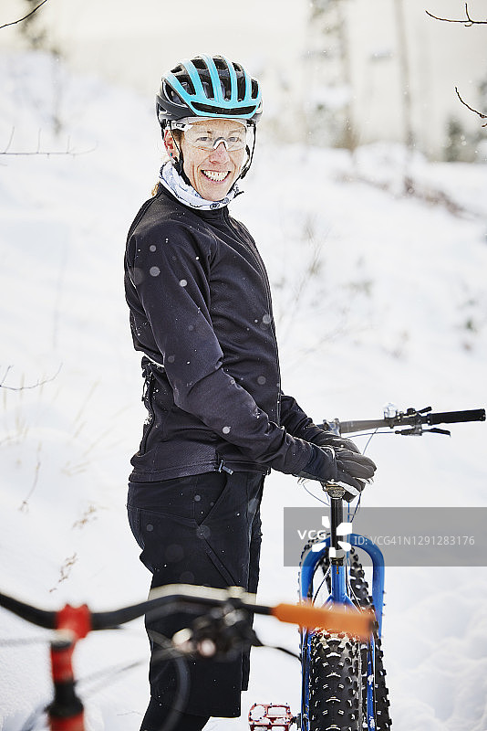 微笑的女骑自行车者在雪地里骑胖胎自行车的肖像图片素材
