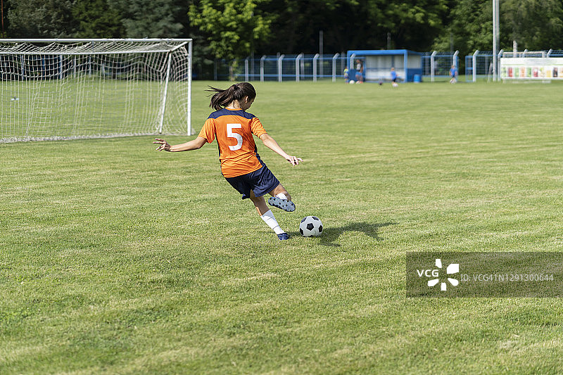 在草皮球场上练习射门的女足球员图片素材