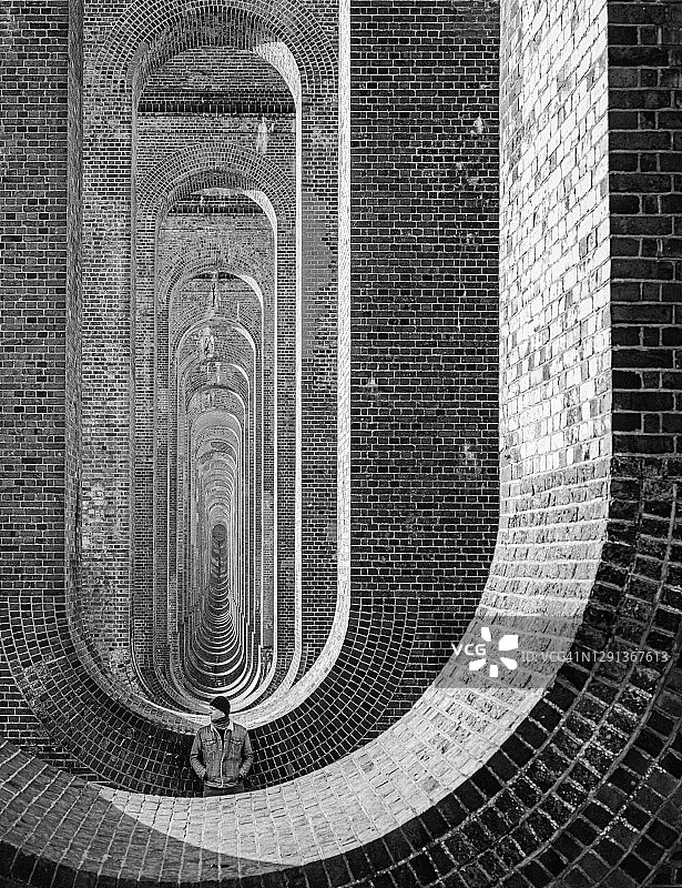 黑白照片：苏塞克斯乌兹河谷高架桥下的男子图片素材