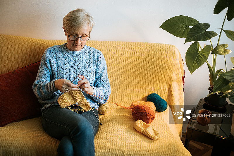 60多岁的老年妇女在客厅里编织，享受休闲时光图片素材