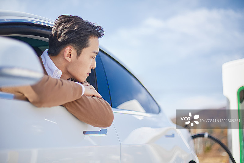 男子对电动汽车充电感到不适图片素材