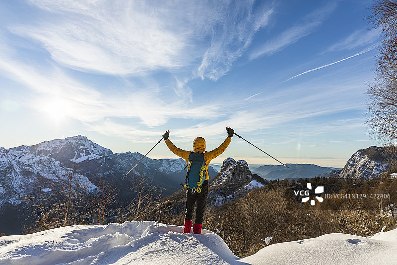 在雪山上高举双手迎接晴朗天空的徒步者图片素材