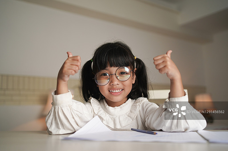 小女孩完成作业后竖起大拇指，教育学习理念图片素材
