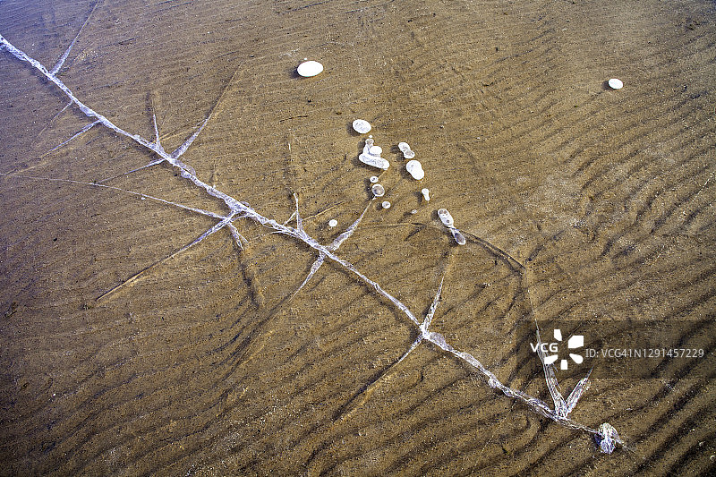 冰冻湖面上清澈冰层裂缝的抽象照片，底部有沙图片素材