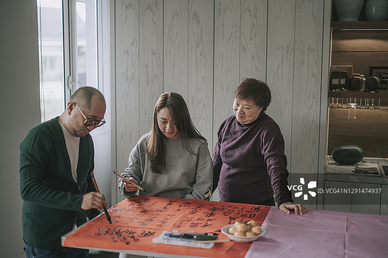 亚洲华人家庭写书法，准备新年装饰图片素材