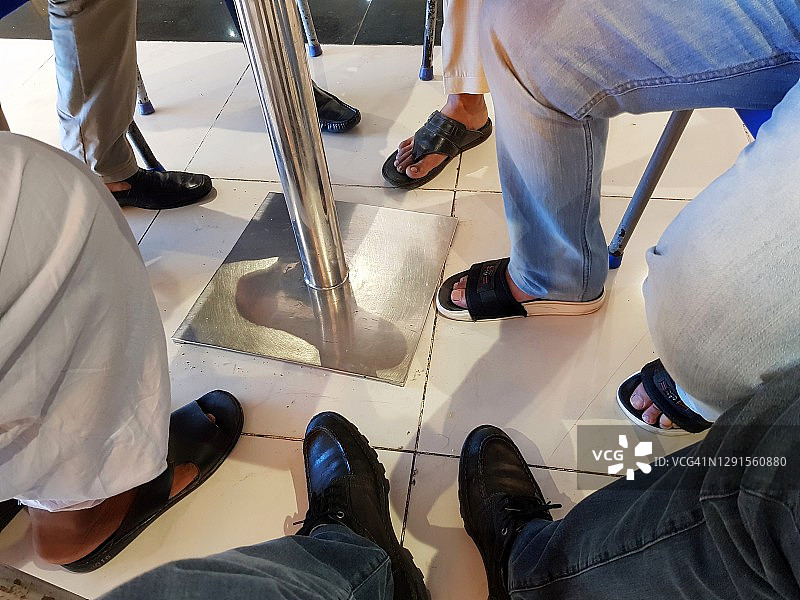 人们坐在瓷砖地板的桌子旁的腿和脚图片素材