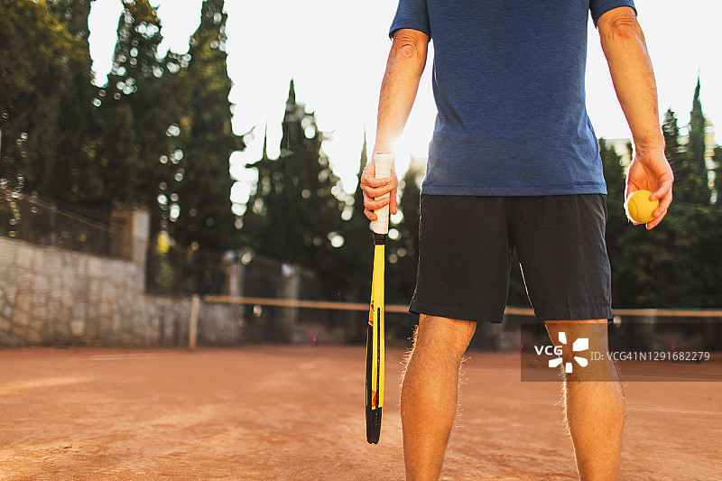 网球比赛概念：男人拿着球拍和球，从后面看图片素材