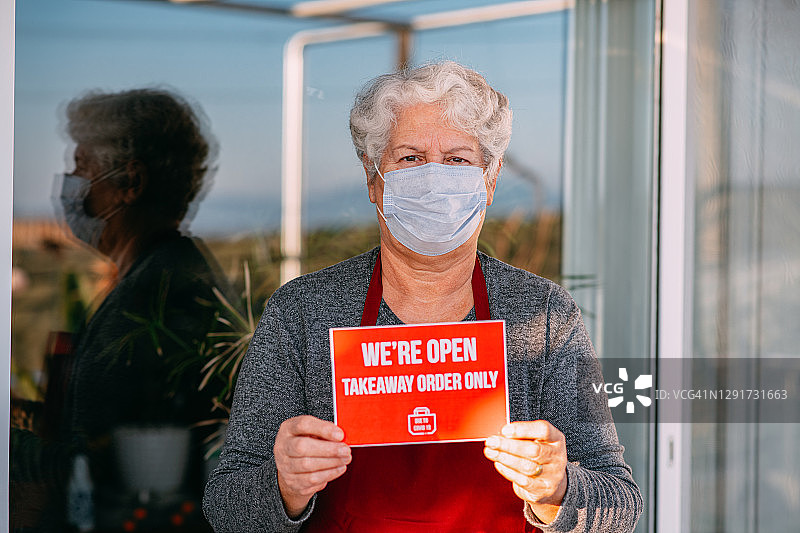 小型企业主戴着口罩，拿着外卖标牌图片素材