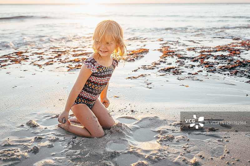 幼儿女孩在海滩上玩耍，珊瑚礁白沙，印度洋海岸，日落，家庭度假，宁静时刻图片素材