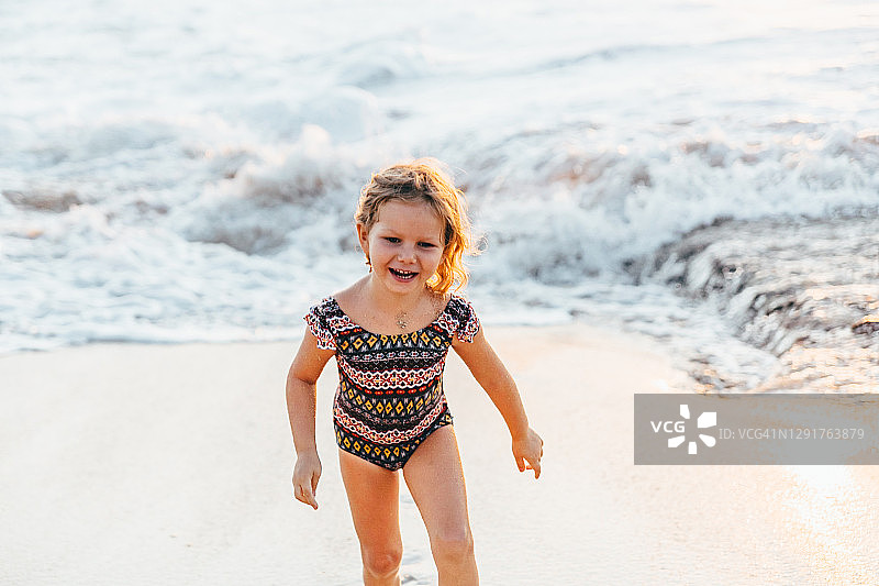 幼儿女孩在海滩上玩耍，珊瑚礁白沙，印度洋海岸，日落，家庭度假，宁静时刻图片素材