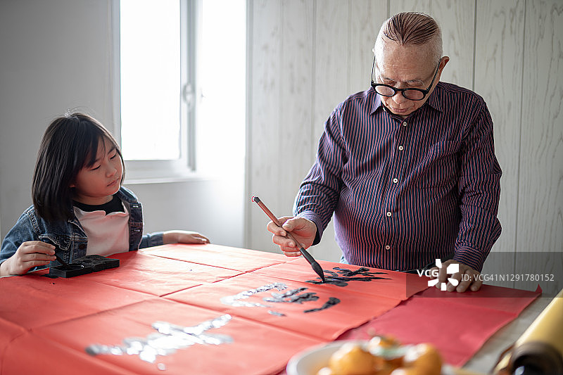 中国祖父和孙女在新年庆祝活动中练习中国书法图片素材
