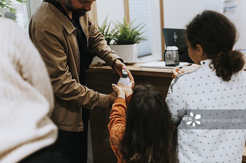 父亲在女儿手上挤洗手液图片素材