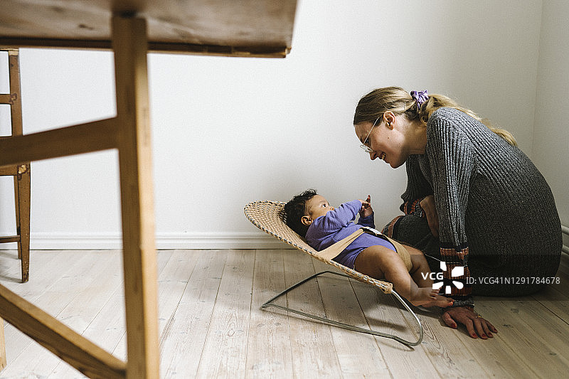 母亲看着躺在摇椅里的婴儿图片素材