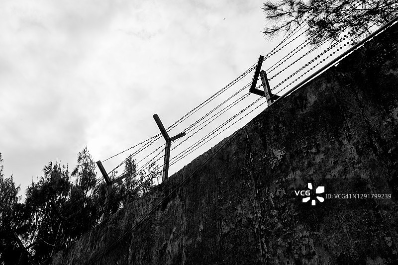 带刺铁丝网的高水泥墙，监狱围墙图片素材