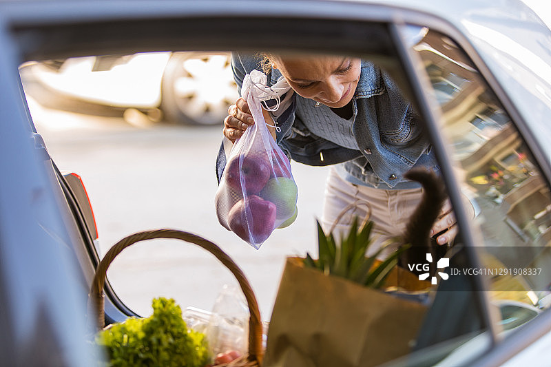 女子将装满食品的袋子装进汽车后备箱图片素材